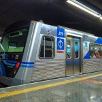 Metrô da linha 1 azul de São Paulo na plataforma de embarque, visto lateralmente.