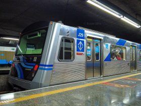 Metrô da linha 1 azul de São Paulo na plataforma de embarque, visto lateralmente.